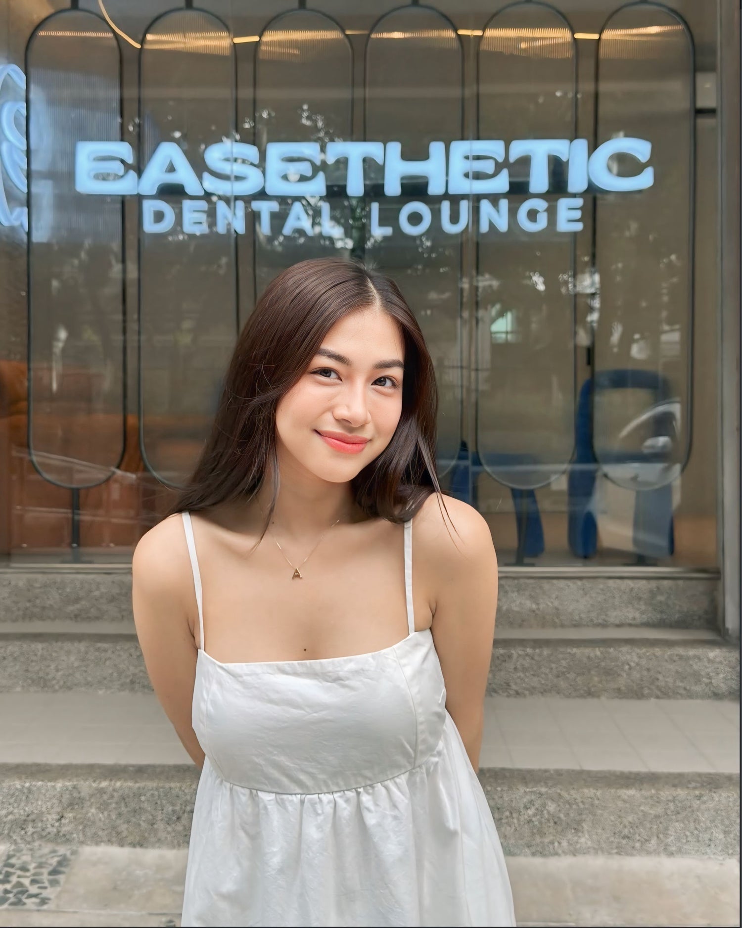 Smiling woman outside Easethetic Dental Lounge, a trusted dental clinic in Quezon City